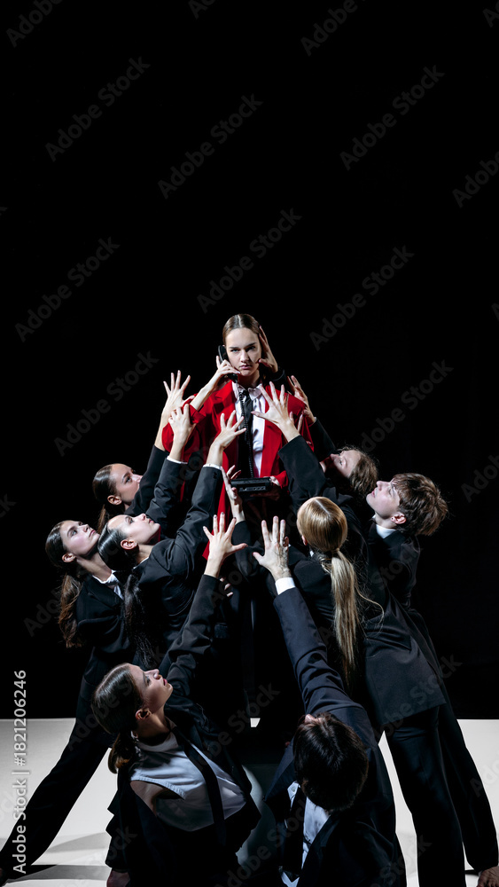 Fototapeta premium Team reaching toward red-clad leader in bold conceptual scene for modern creative marketing visuals. Concept of brand emotion, visual storytelling, eye-catching contrast and high-impact promos.