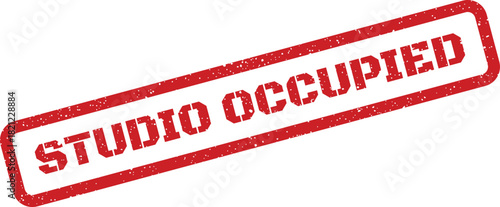 Textured red rubber stamp displaying STUDIO OCCUPIED message for indicating workspace status or resource unavailability