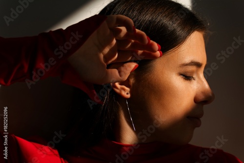 Woman in red dress posing in dramatic sunlight