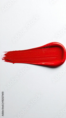 A vibrant red paint stroke, elongated and slightly curved, on a white background