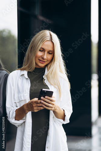 Young woman talking on the phone, standing by the business center