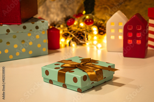 Christmas decorations: gifts wrapped in paper, candle, Christmas baubles and ornaments, and a garland glowing with warm light.