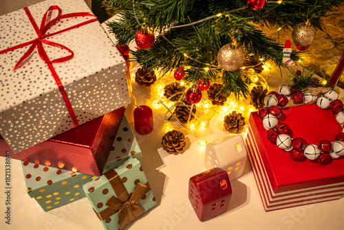 Christmas decorations: gifts wrapped in paper, candle, Christmas baubles and ornaments, and a garland glowing with warm light.