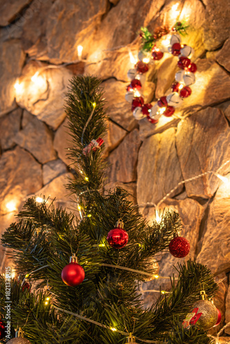 The Christmas tree is decorated with a garland and red baubles. A wreath made of jingle bells.