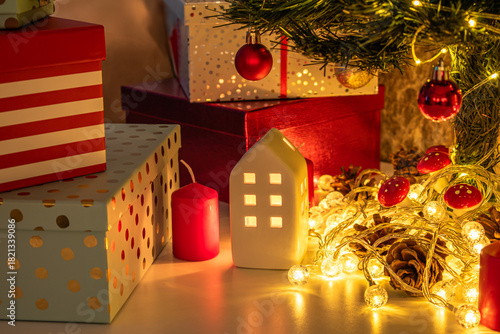 Christmas decorations: gifts wrapped in paper, candle, Christmas baubles and ornaments, and a garland glowing with warm light.