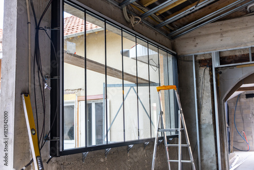 Gros plan sur une grande verrière installée dans un bâtiment en travaux, révélant la structure métallique, le vitrage et l’avancement du chantier.