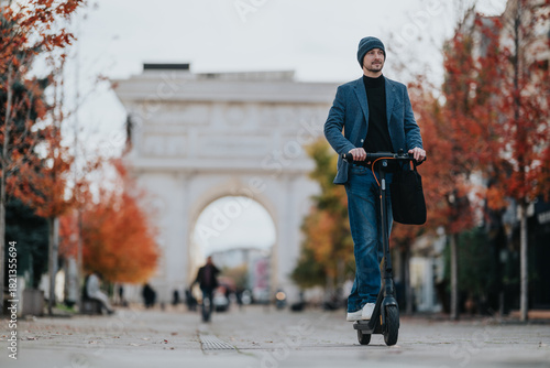 A stylish man rides an electric scooter along a tree-lined avenue in autumn, wearing a beanie and blazer. An urban scene of casual commuting and city life in cool weather.