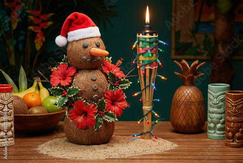 Tropical Christmas celebration with a coconut snowman in a Santa hat, a tiki torch with lights, and tiki mugs. Mele Kalikimaka holiday concept.