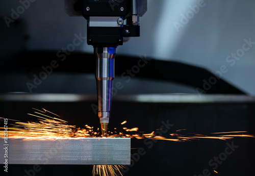 Close up automation laser cutting machine working with metalwork is drilling holes metal rods it causing sparks on industrial factory, copy space