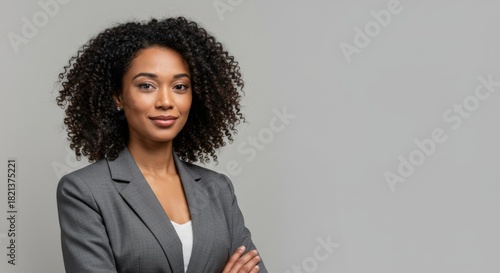 Confident african american woman in a grey suit with arms crossed, smiling at camera. Professional business concept.