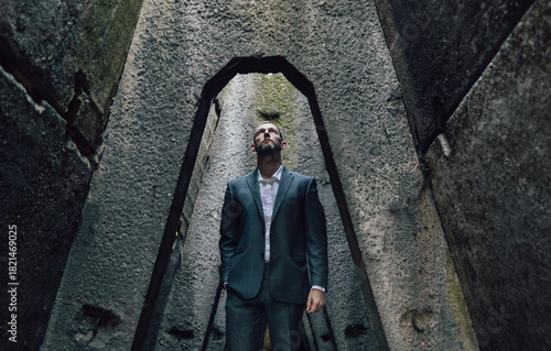 Businessman in suit standing in concrete corridor looking up. Sci-fi concept background, lifestyle