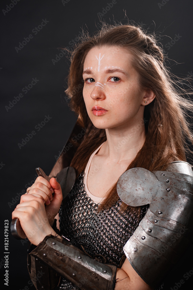 Obraz premium Portrait of a young woman, fantasy warrior in armor with a sword in her hands isolated on a dark background.