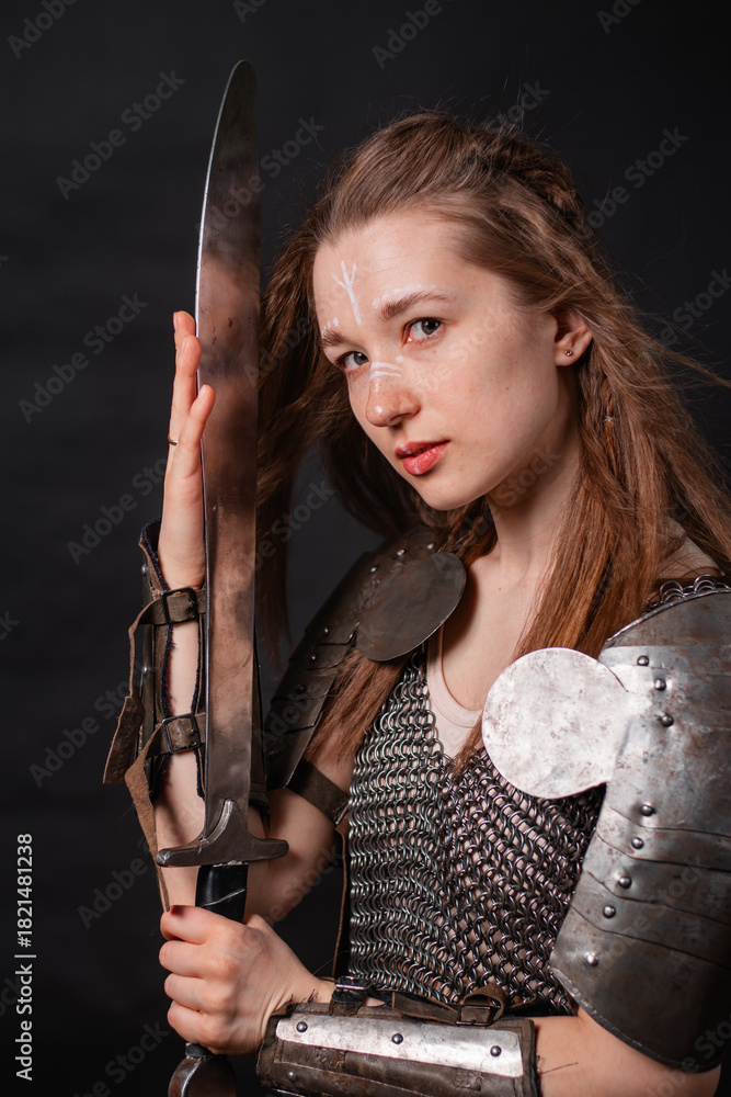 Obraz premium Portrait of a young woman, fantasy warrior in armor with a sword in her hands isolated on a dark background.