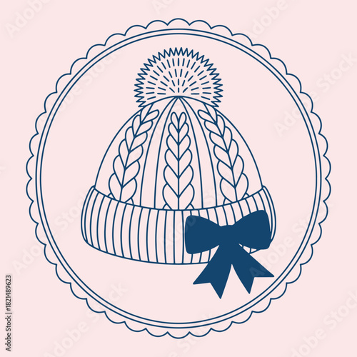 Dark blue knitted winter hat with pom and bow on pale pink background knitted hat bobble hat