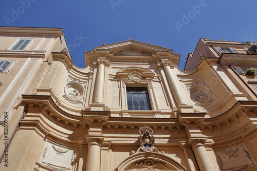Baroque facade of the Church of Santa Caterina da Siena a Via Giulia in Rome, Italy. Curved lines, columns, and ornate carvings under a bright blue sky.