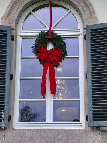 weihnachtliches Fenster grüner Kranz mit roter Schleife und weiße Sprossenfenster, adventliche Stimmung