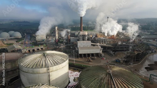 Aerial drone cinematic shot of industrial sugar production factory with silos chimney stacks smoke plumes in foggy winter Bury Saint Edmunds United Kingdom
