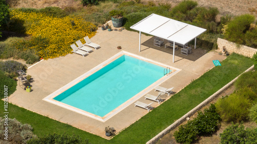 An aerial view of a swimming pool in a country villa. There's no one in the garden.