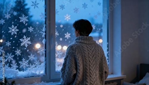 Person in sweater looking out window decorated with snowflake stickers