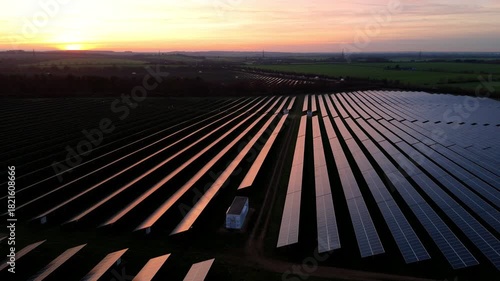 Drone aerial perspective of solar panels photovoltaic energy generation glowing winter sunset skies rural Newmarket England United Kingdom