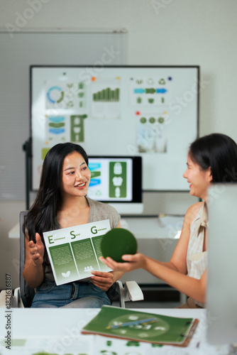 Businesswomen discussing ESG strategy holding green documents