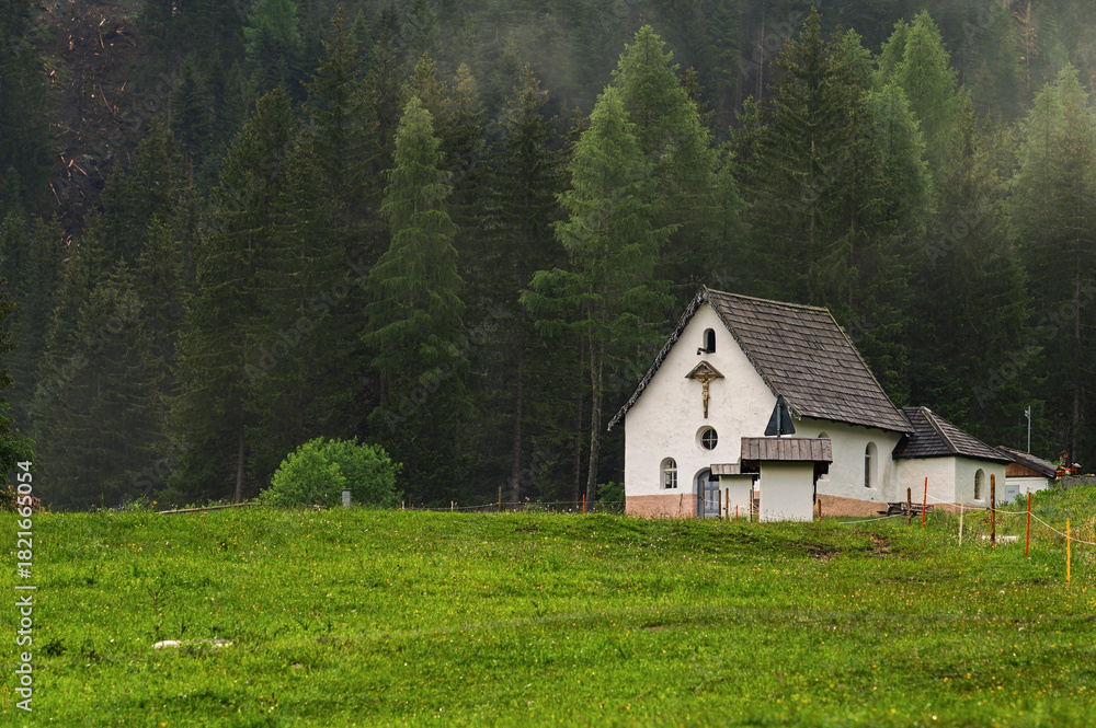 Obraz premium the little church of the crucifix at the beginning of San Nicolò valley in a foggy morning, Val di Fassa, Dolomites, Italy