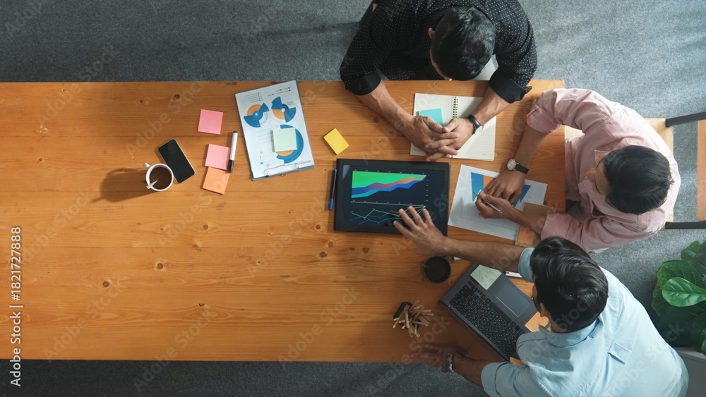 Obraz premium Top view of skilled project manager talking about financial graph to investors while sitting at meeting table with data analysis document. Diverse team discussing and brainstorming idea. Convocation.