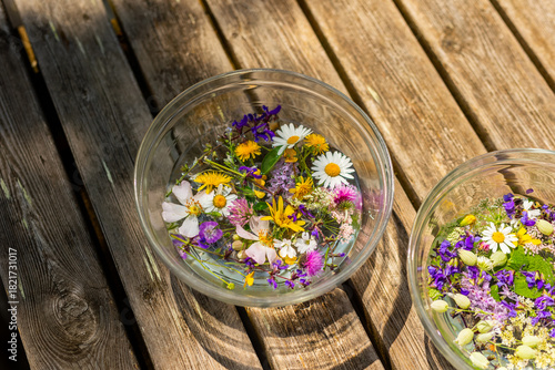 Canvastavla St John's water in glass bowls with wildflowers and herbs on a wooden table