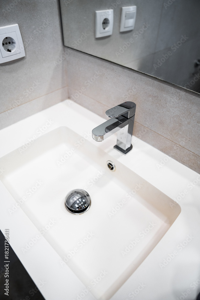 Fototapeta premium Modern bathroom sink with chrome faucet and mirror reflecting minimalist clean interior design details