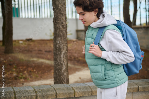Teen Boy With Backpack Running Outdoors In Park During School Day