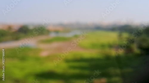 A peaceful riverside landscape featuring lush green fields, flowing water, and a clear blue sky. The natural scenery creates a calm and refreshing atmosphere.