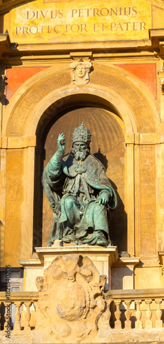 Bronze King Statue On Ornate Arch Facade Of Historic Monument, Regal Gesture, And Sunlit Architecture