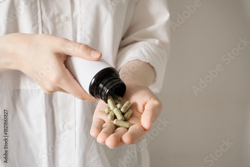 Female hands pouring dietary supplements or medicine into an open palm