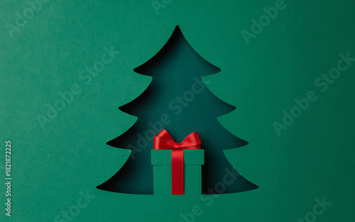 Christmas tree silhouette revealing a wrapped gift with red ribbon