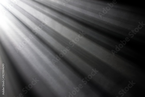 Diagonal light rays shining across a dark textured surface.