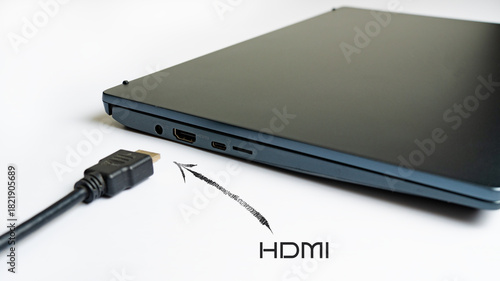 Is connecting black HDMI cable into HDMI port of the modern laptop on white background. Arrow pointer with the label HDMI