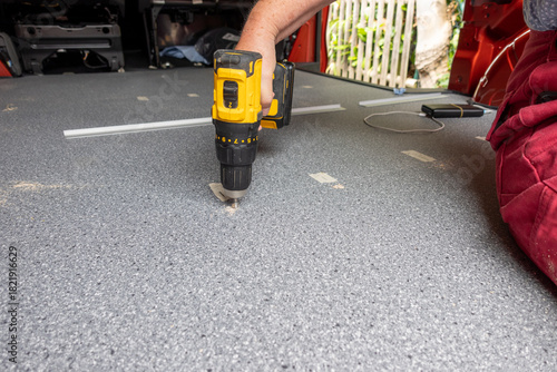 Frau verschraubt eine Bodenplatte im Wohnmobil Camper van conversion