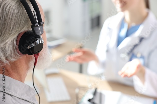 Patient with audiometric headphones undergoing hearing test in clinic, selective focus. Space for text