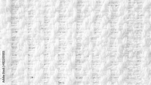 Background from white coarse canvas texture. Textured white knit fabric showcases intricate weaving patterns and soft fibers suitable for cozy apparel and home textiles.