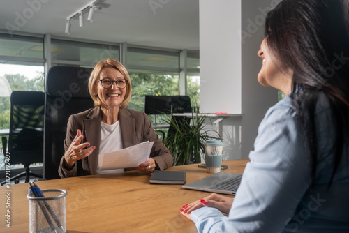 Happy bank manager smiling with a client after a successful agreement in the office.