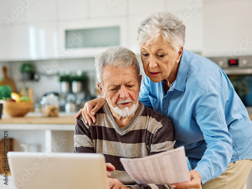 Canvas-taulu Senior couple checking bills and calculating expenses using a laptop at home, de