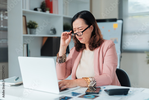 Foto Mature Asian businesswoman needing reading glasses, struggling with vision and e
