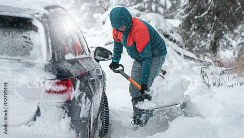 Clearing snow from a car stuck in a snowdrift using a shovel.