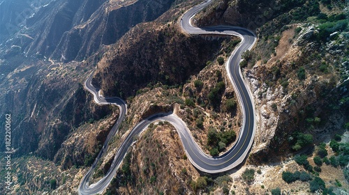 Aerial drone view of a dangerous winding mountain road switchbacks carving through arid rocky landscape