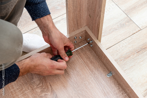 Bild auf Leinwand Man handyman furniture assembler assemble table with hand screwdriver and screws