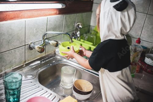 A little girl washing dishes