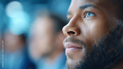 Close-up portrait of young man gazing forward in soft modern lighting, expressing confidence, purpose and contemplation in a contemporary professional environment.