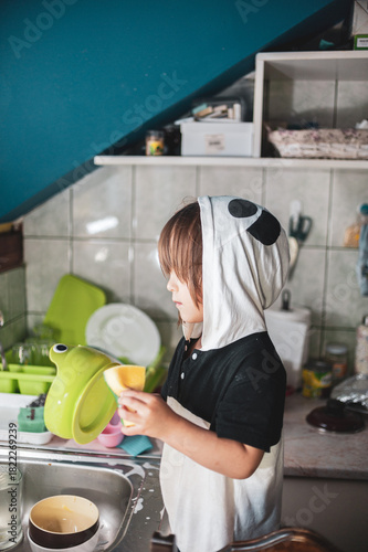A little girl washing dishes