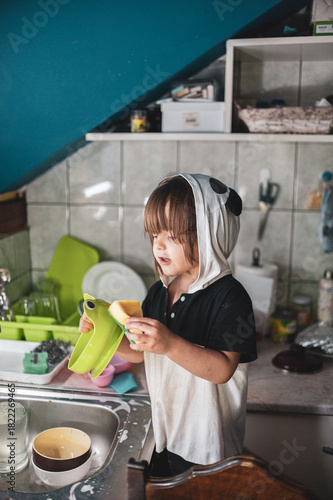 A little girl washing dishes