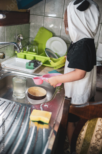 A little girl washing dishes